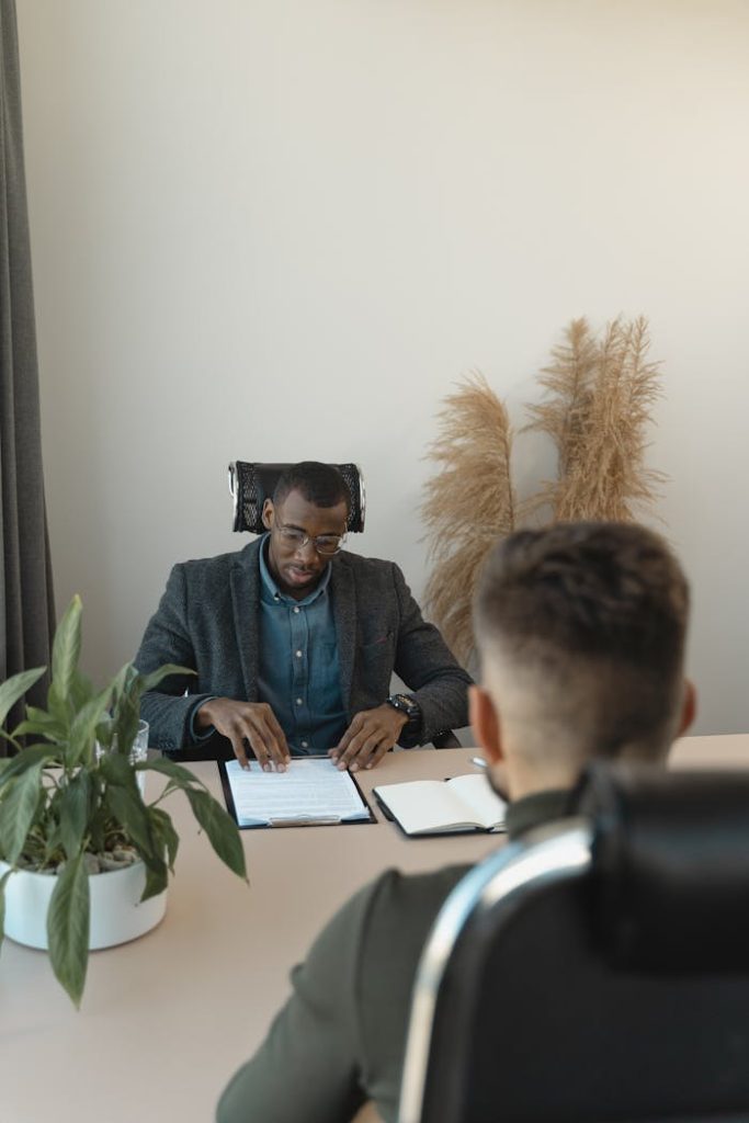 Two professionals engaged in a job interview in a modern office setting with greenery.